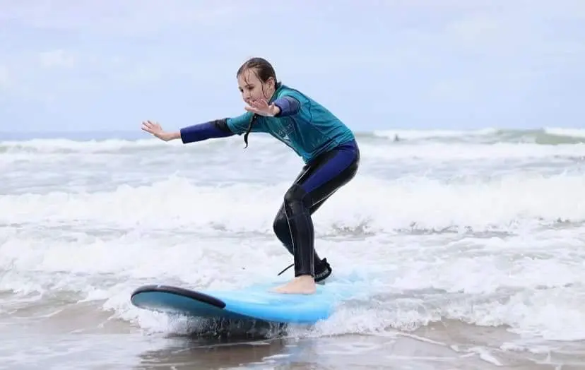A beginner surfer riding a small wave during a North Devon lesson